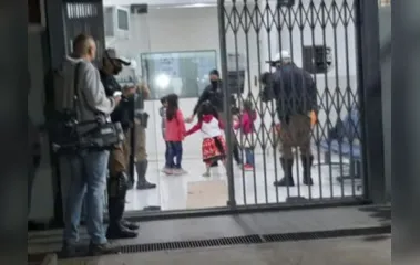Crianças brincam com policiais enquanto pais são presos